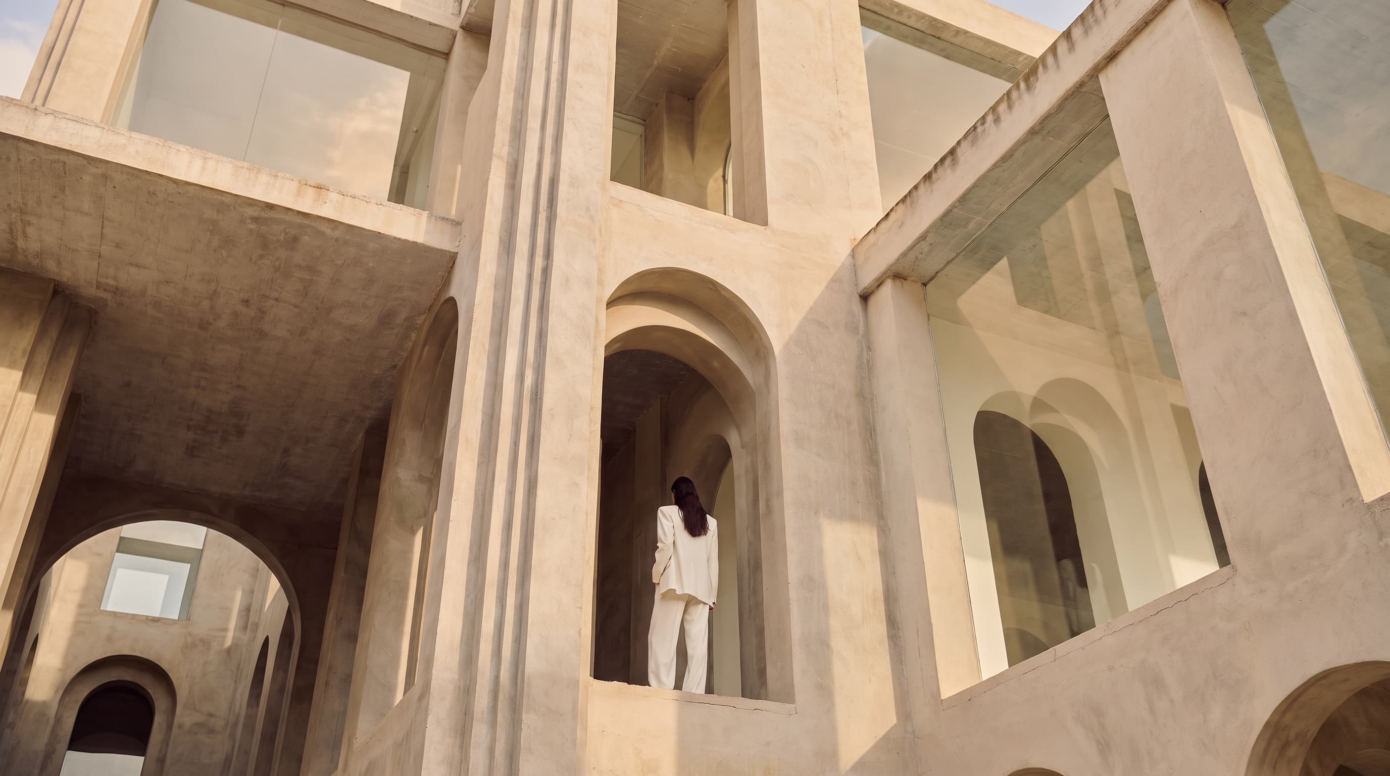 Figura vestita di bianco in un'architettura razionalista ad archi